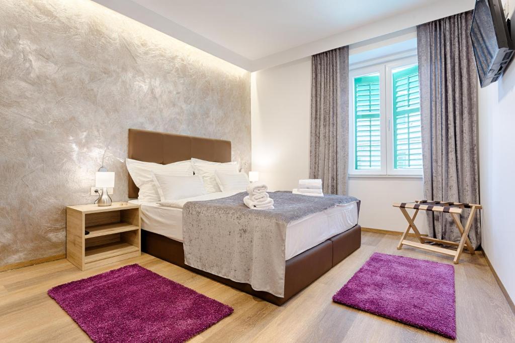 um quarto com uma cama grande e tapetes roxos em Central Pearl by Nono Ban Rooms em Split