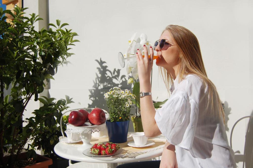 a woman sitting at a table drinking from a cup at Residence Mimosa in Rimini