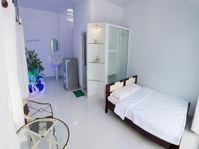 a bedroom with a bed and a chair in a room at Nostress Guest House in Mui Ne