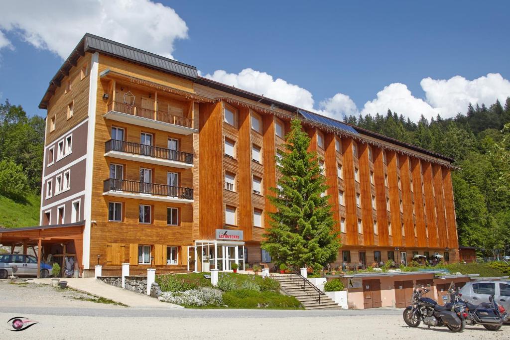 un grand bâtiment avec une moto garée devant lui dans l'établissement Résidence Le Fontenay, à Plateau dʼAssy