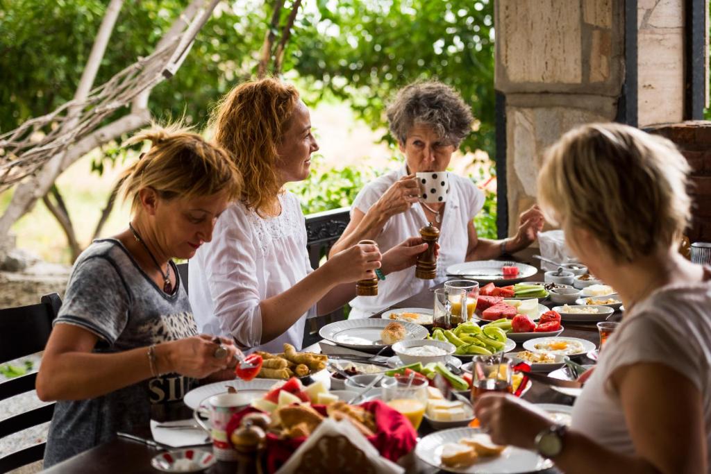 un grupo de personas sentadas alrededor de una mesa comiendo comida en Agora Pansiyon, en Kapıkırı