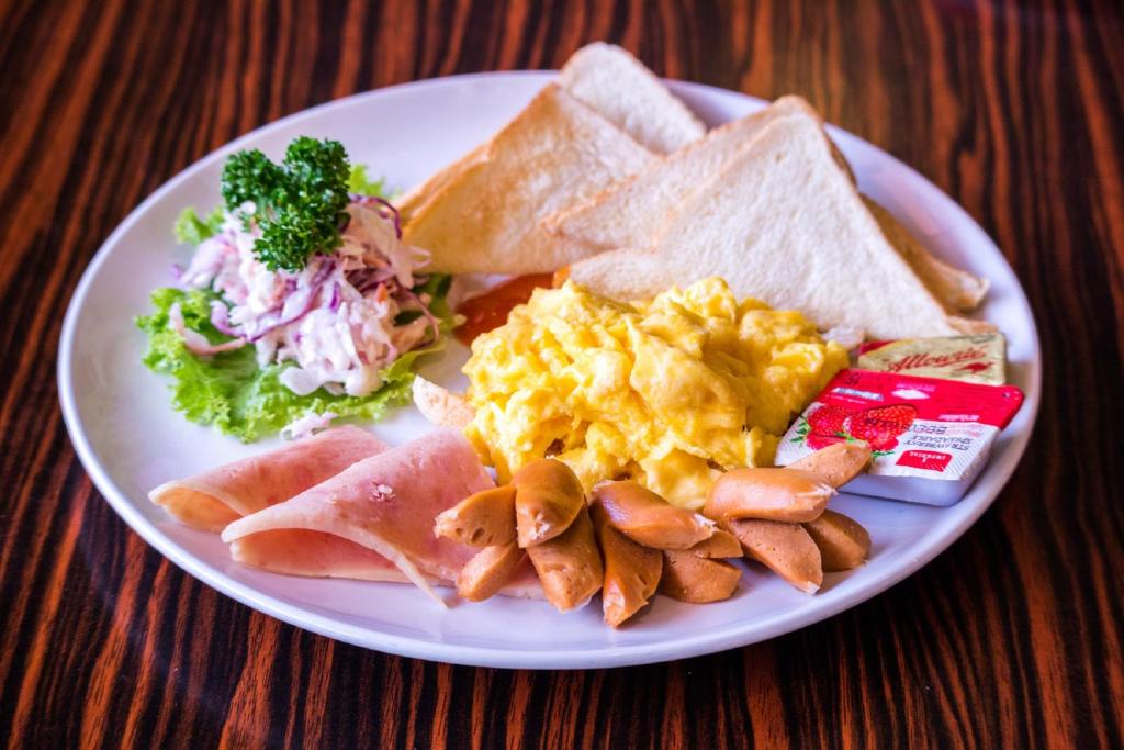 A scrambled-egg breakfast plate with ham, sausage, toast and salad.