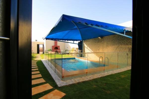 una sombrilla azul grande junto a la piscina en Danat Alnakheel Chalet, en Buraidah