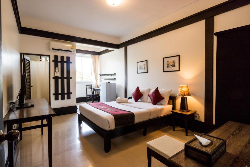A bright double room with a bed, desk, seating area and large window.