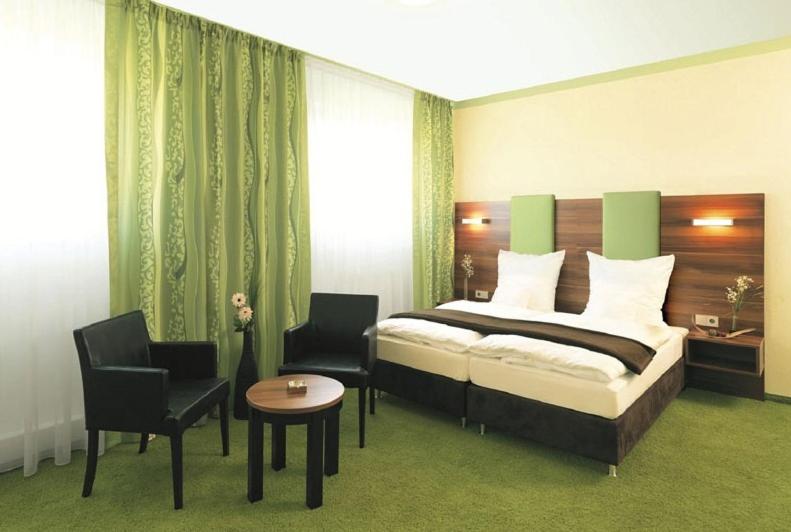 1 Schlafzimmer mit einem Bett, 2 Stühlen und einem Tisch in der Unterkunft Hotel und Cafe Paso in Vierkirchen