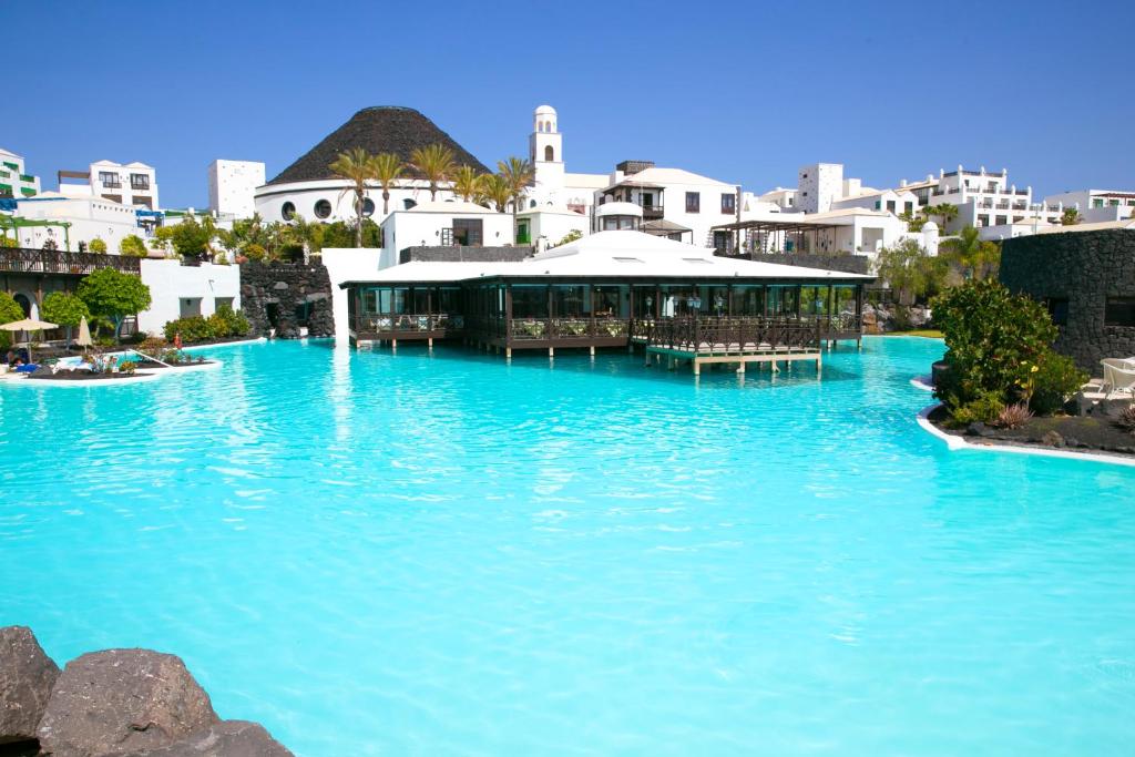 een groot zwembad met blauw water in een resort bij Hotel LIVVO Volcán Lanzarote in Playa Blanca