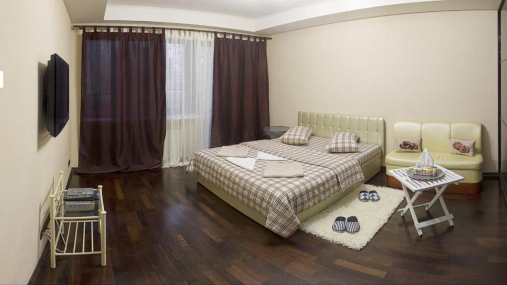 Schlafzimmer mit einem Bett, einem Tisch und einem TV in der Unterkunft Kyiv downtown apartment on Saksaganskogo street 87 in Kiew