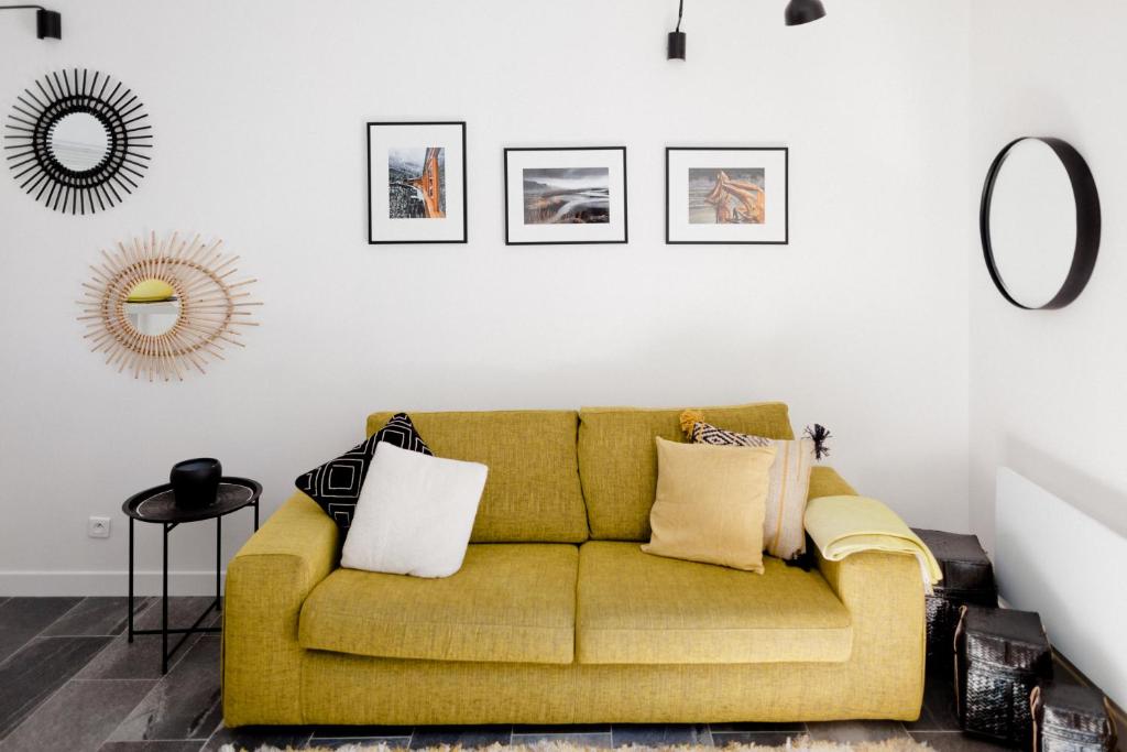 a living room with a yellow couch with pillows at L'Orangeraie et la Palmeraie d'Endoume in Marseille