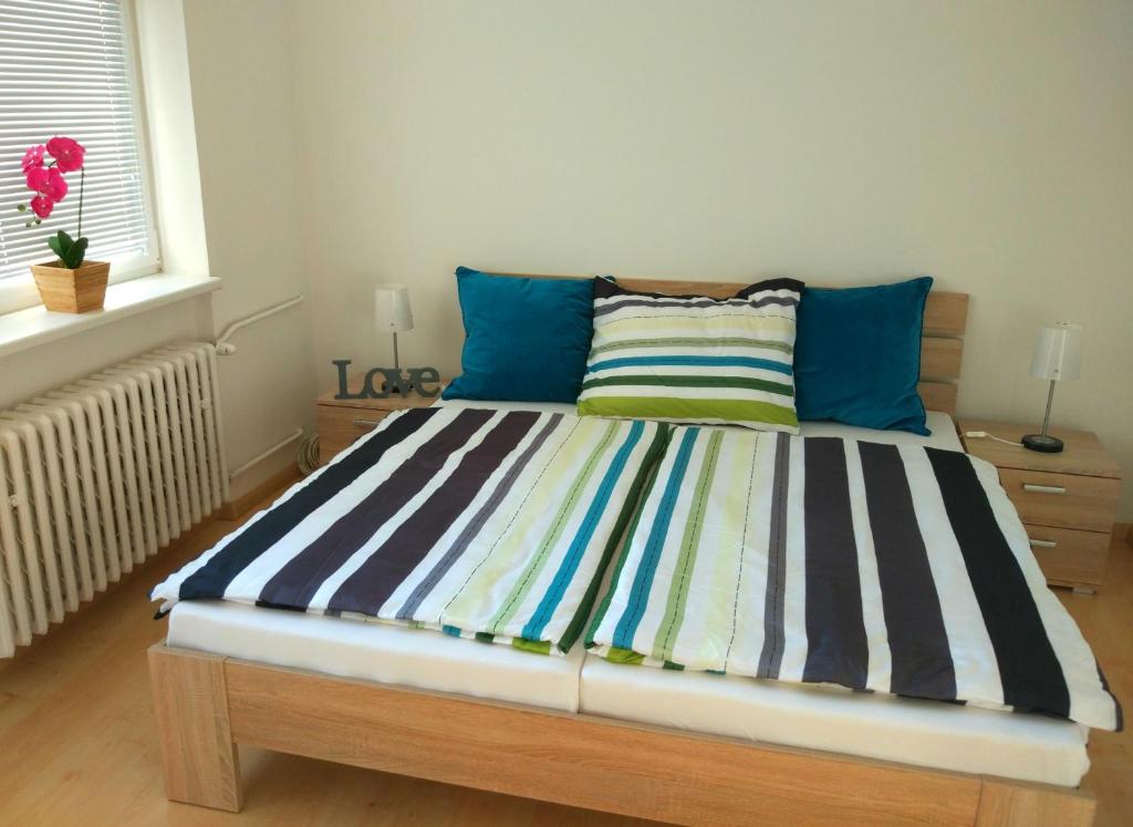łóżko z paskowym kocem i niebieskimi poduszkami w pokoju w obiekcie Riverview Apartment Bratislava w Bratysławie