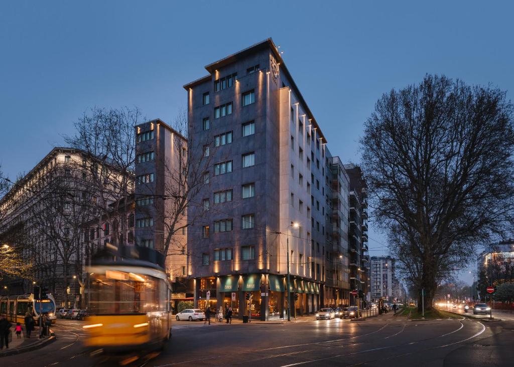 un autobús conduciendo por una calle frente a un edificio alto en Windsor Hotel Milano, en Milán