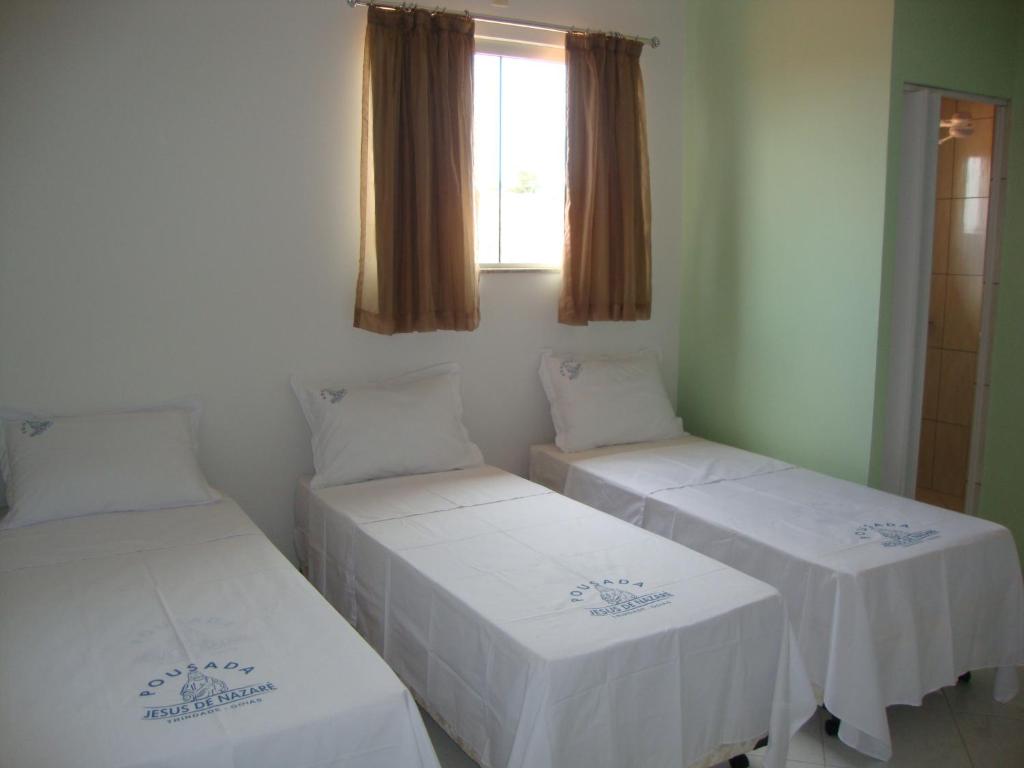 two beds in a room with a window at Pousada Jesus De Nazare in Trindade