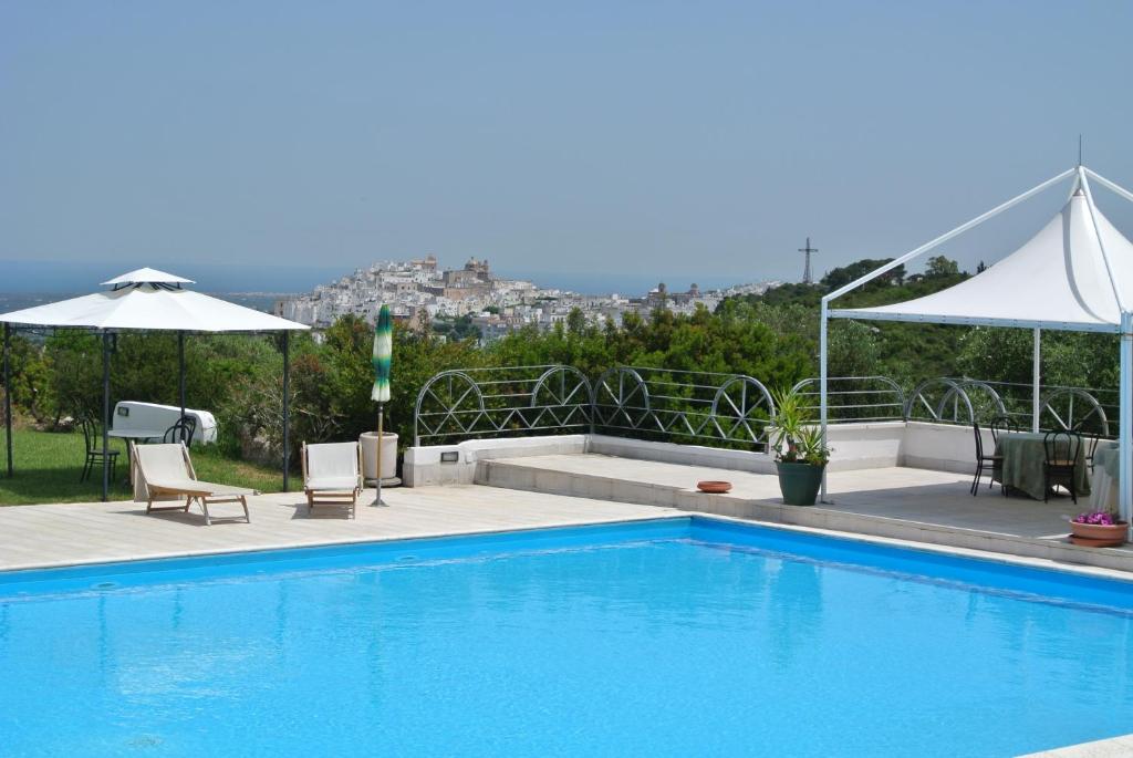 a swimming pool with two chairs and an umbrella at Hotel Incanto in Ostuni