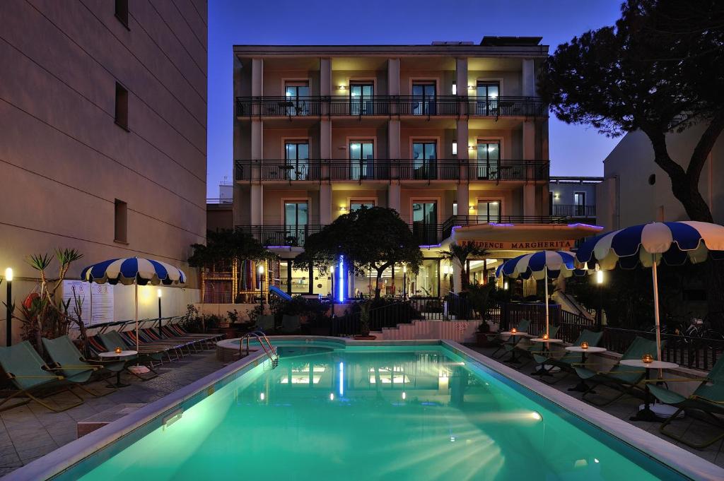 a swimming pool in front of a hotel at night at Residence Margherita in Cattolica