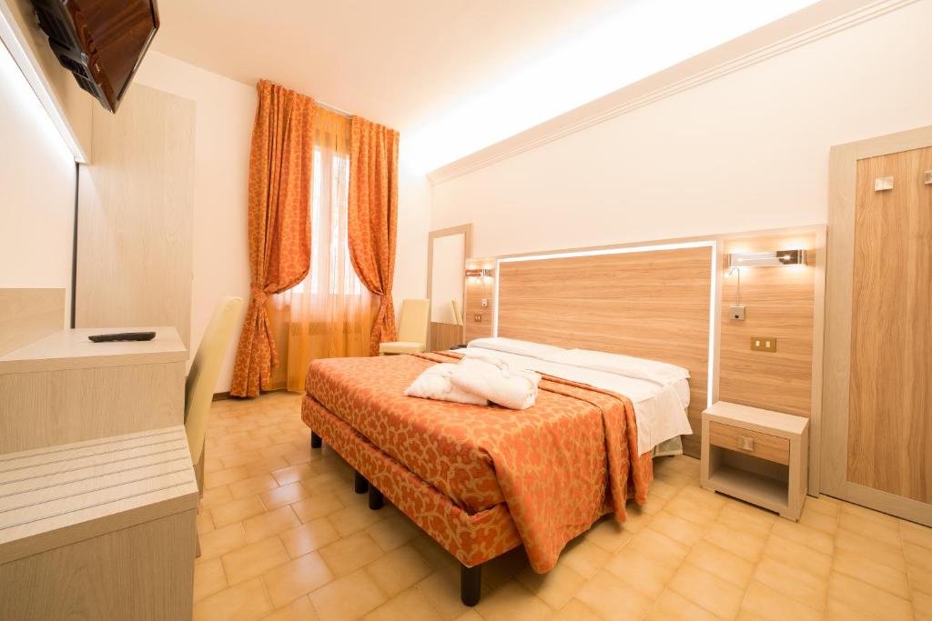 Cette chambre d'hôtel comprend un lit avec une couverture orange. dans l'établissement Hotel Carancini, à Salsomaggiore Terme