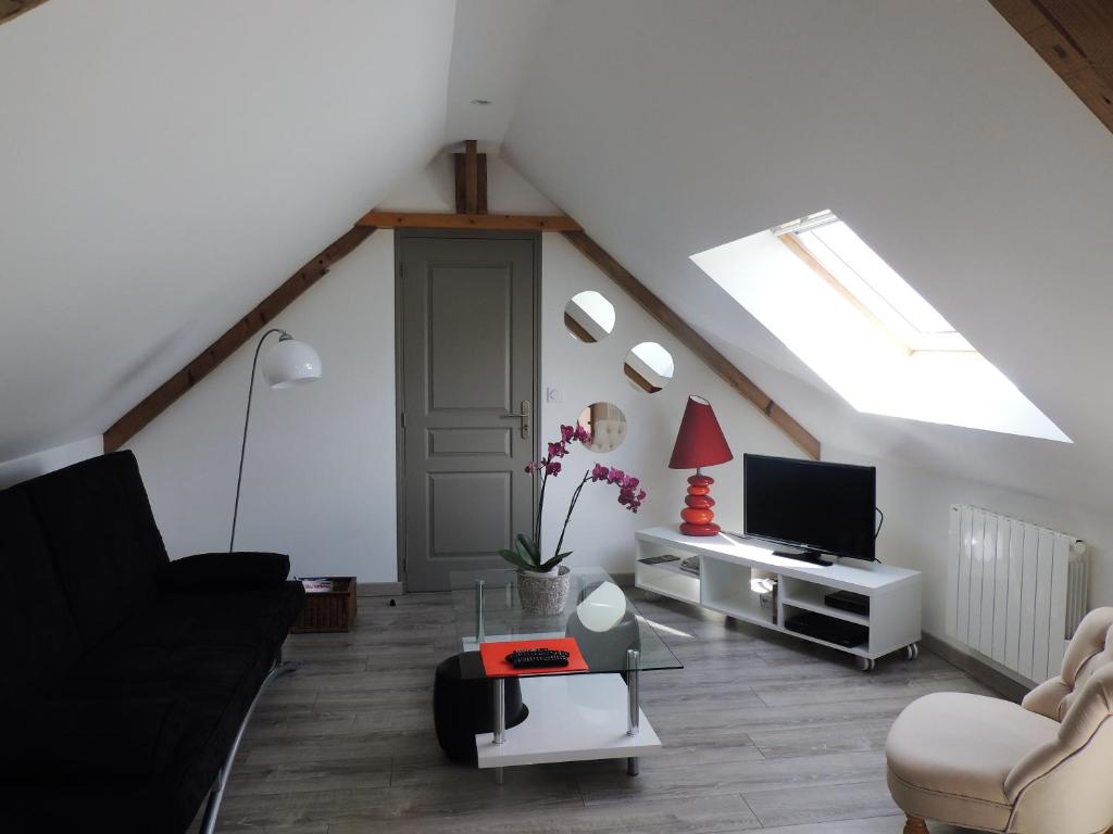 a living room with a couch and a tv at le petit Vauquelin in Sommervieu