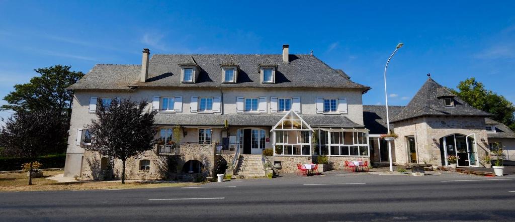 una gran casa de piedra con techo gris en Logis Hotel Le Relais du Teulet, en Goulles