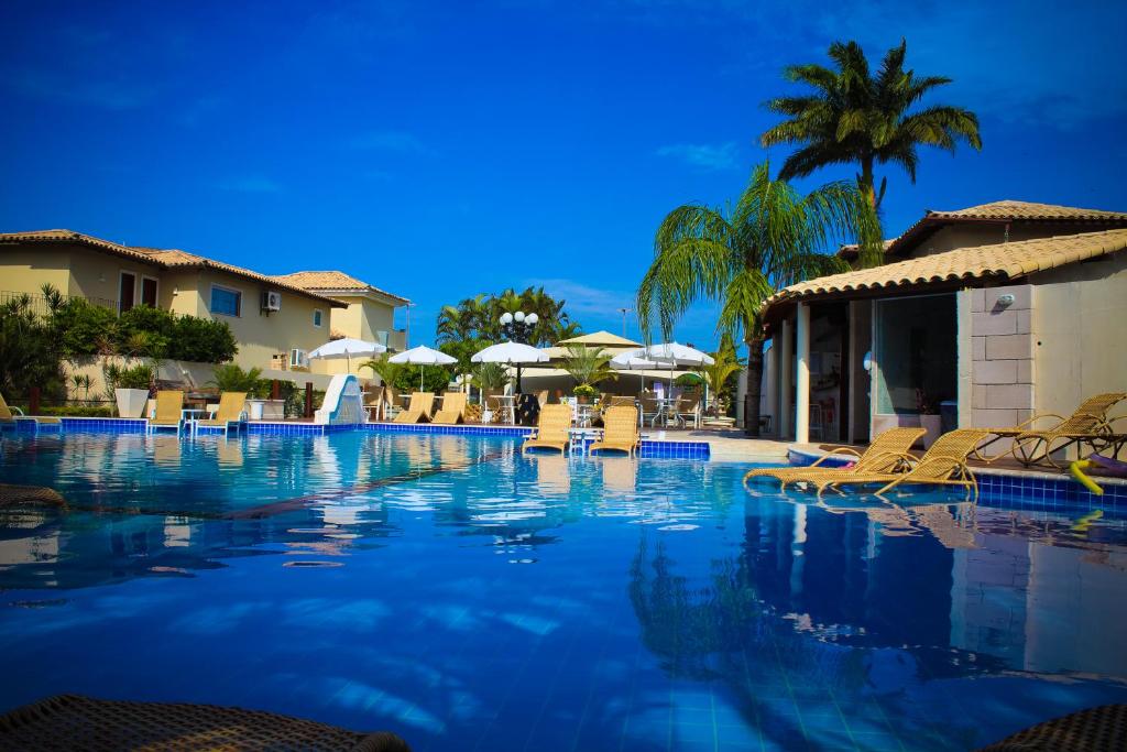 ein großer Pool mit Stühlen und Sonnenschirmen in der Unterkunft Hotel Don Quijote Búzios in Búzios