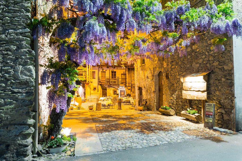 un edificio con fiori viola appesi ad esso di Contrada Beltramelli a Villa di Tirano