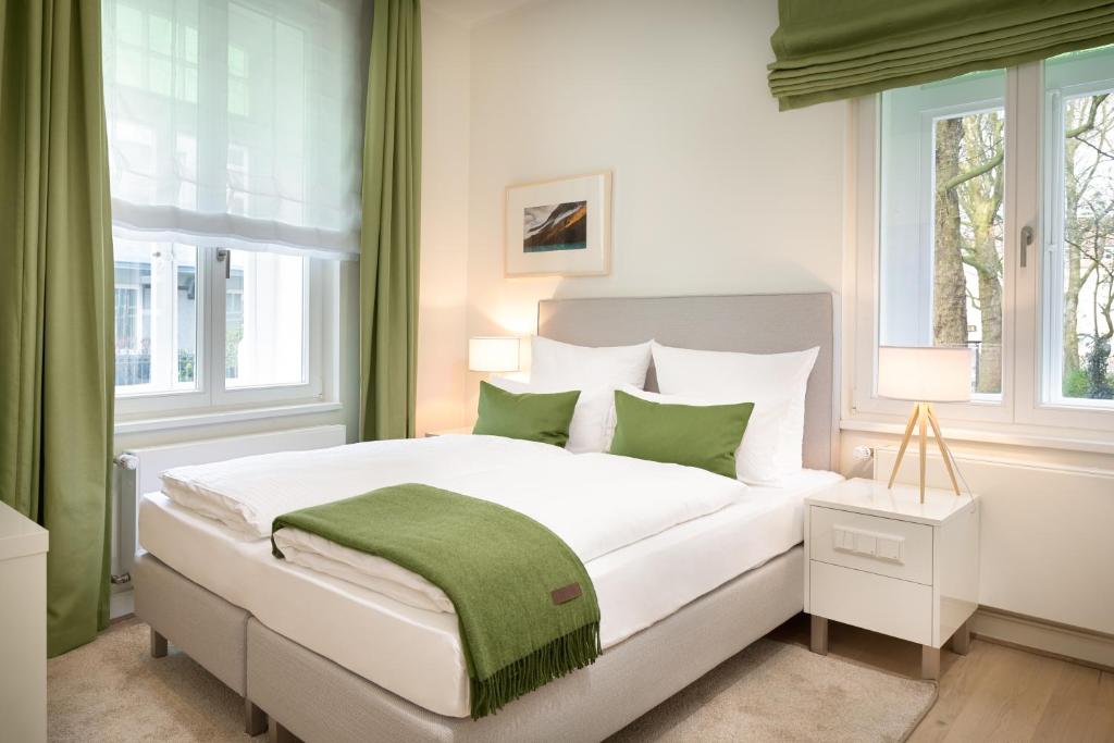 um quarto com uma grande cama branca com toques de verde em Bergmann Boardinghouse Osnabrück em Osnabrück