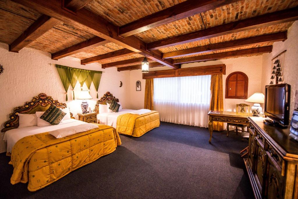 a hotel room with two beds and a television at Hotel La Mansion del Sol in Guadalajara