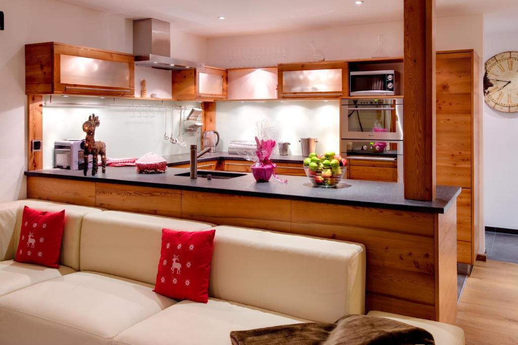 a living room with a couch and a kitchen at Luxury Chalets & Apartments by Mountain Exposure in Zermatt