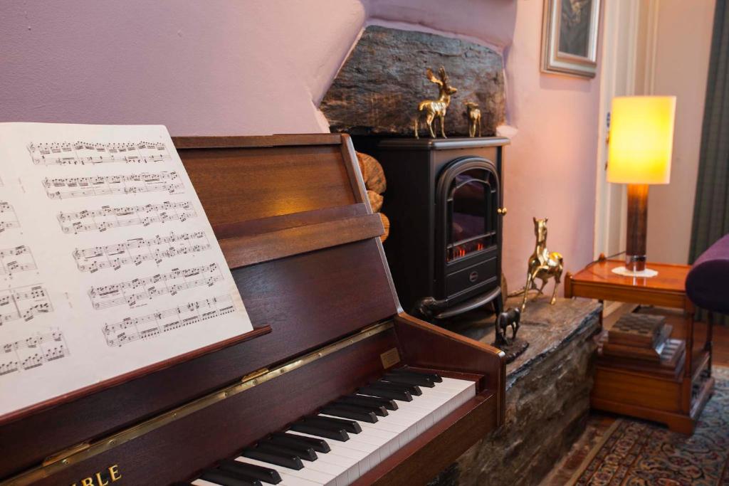 a piano in a living room with a stove at Port Charlotte Hotel in Port Charlotte