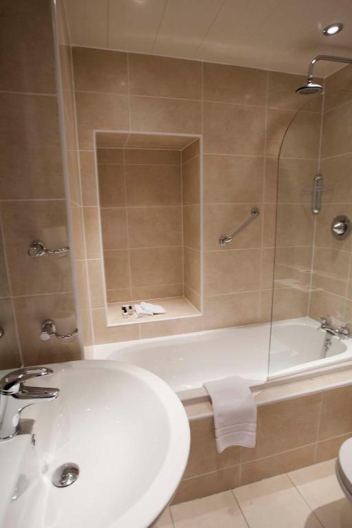 a bathroom with a tub and a sink and a toilet at Port Charlotte Hotel in Port Charlotte