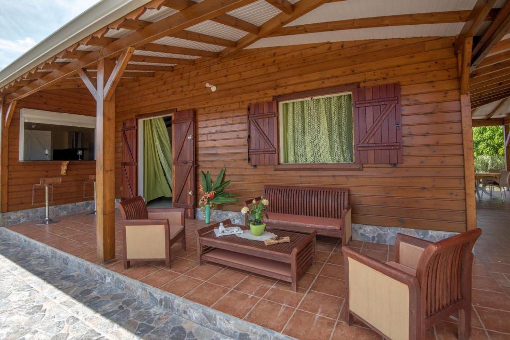 eine Veranda eines Holzhauses mit Stühlen und einem Tisch in der Unterkunft Bienvenue Au Tropic Venucia in Port-Louis