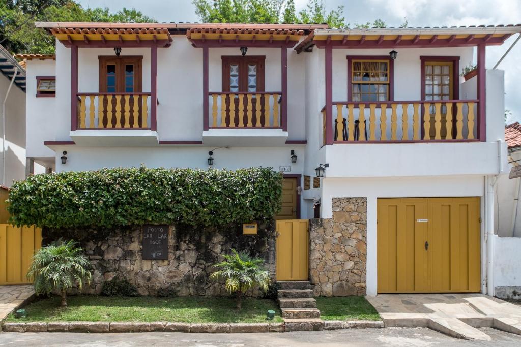 a house with yellow doors and a stone wall at Pouso Lar Doce Lar in Tiradentes