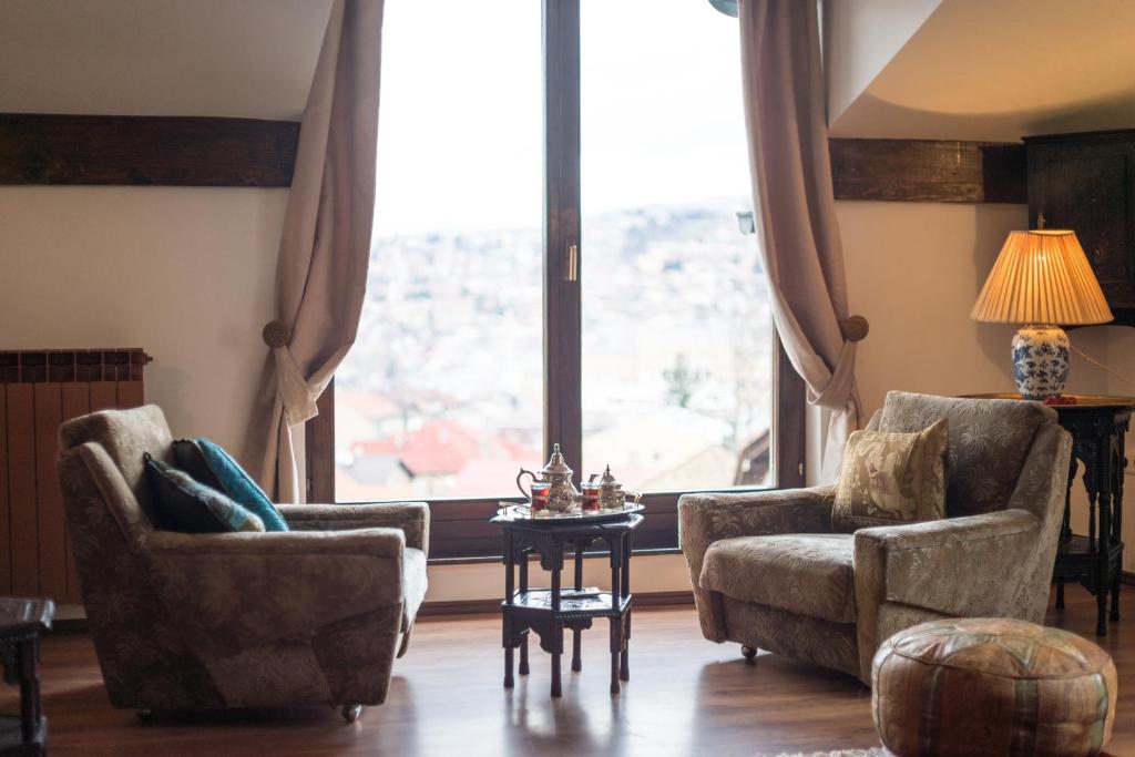 een woonkamer met 2 stoelen, een tafel en een raam bij Old Town Apartment in Sarajevo