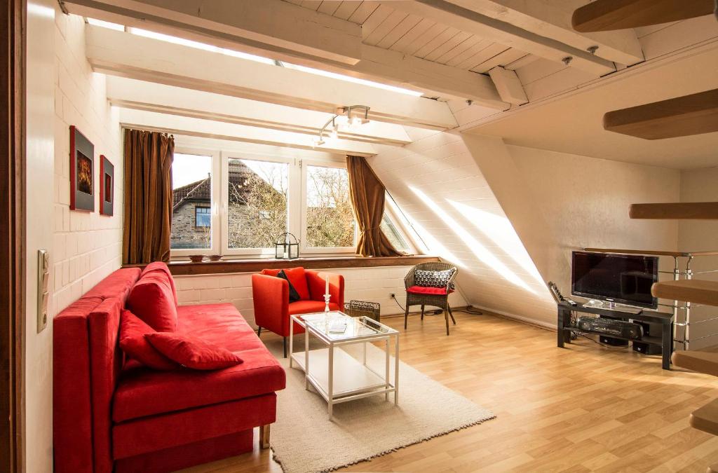 sala de estar con sofá rojo y mesa en Ferienwohnung Gilg en Cuxhaven