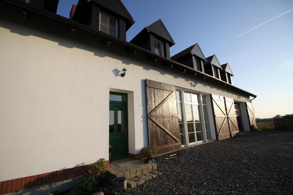 un edificio blanco con una puerta verde y ventanas en Mylin en Chrzypsko Wielkie