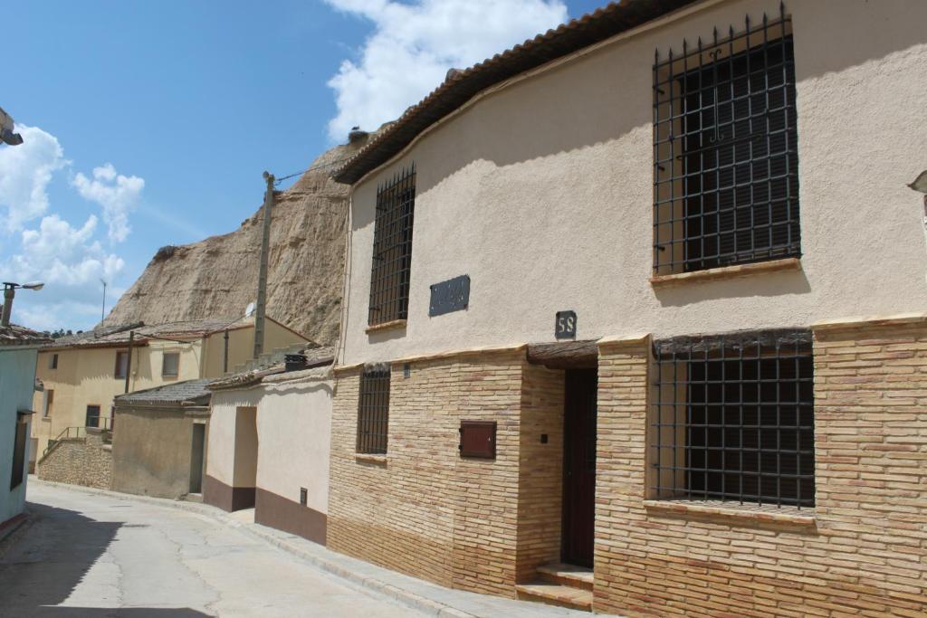 an old brick building on a street with a hill in the background at Casa el Aljibe in Lanaja