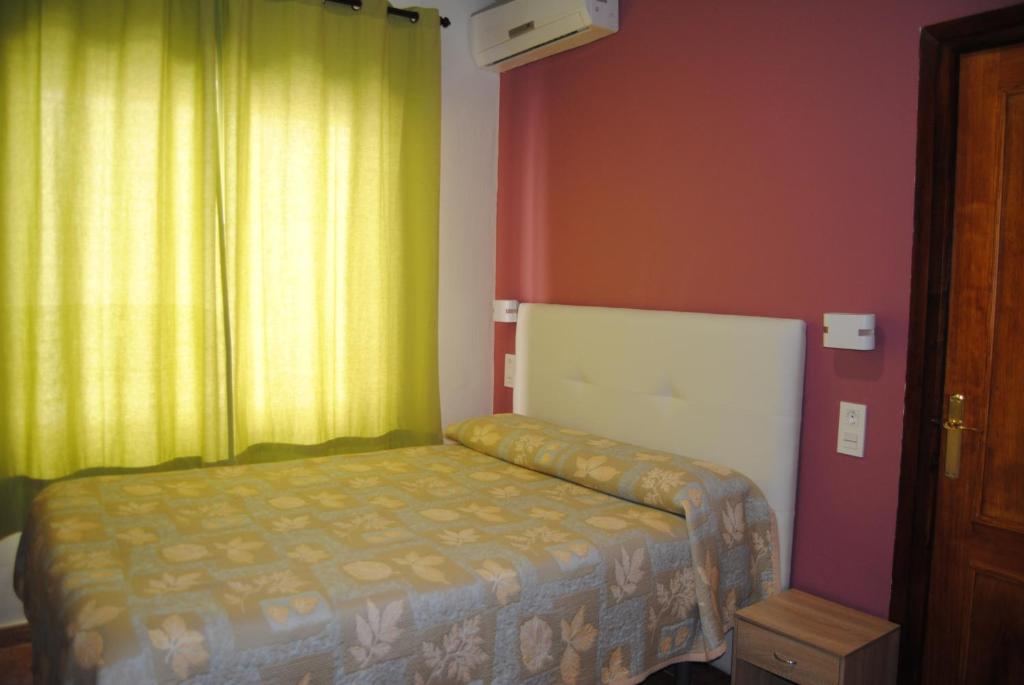 Habitación pequeña con cama y ventana en Hostal Rocamar, en Almuñécar