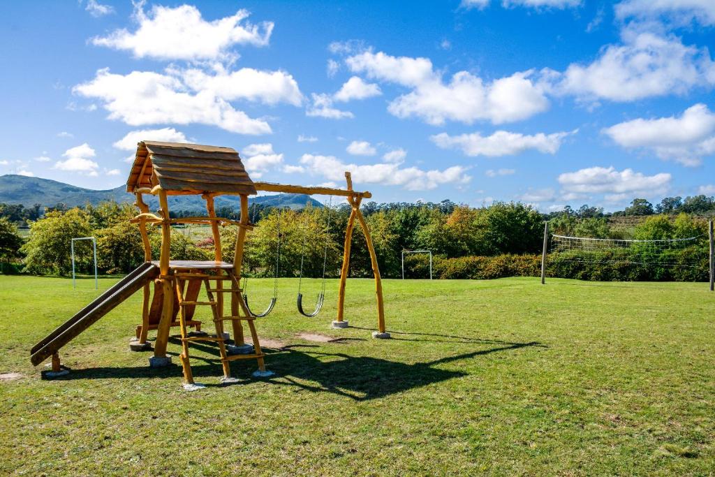 a playground with a wooden slide in a field at Cabañas Luna Lunera in Tandil