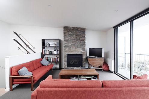 a living room with a red couch and a fireplace at Apartment K2 15 in Mount Buller