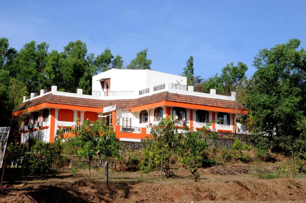 an orange and white house on a hill with trees at Riverside Inn in Koynanagar