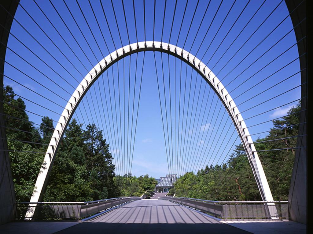 a white arch bridge over a road with trees at Lake Biwa Otsu Prince Hotel in Otsu