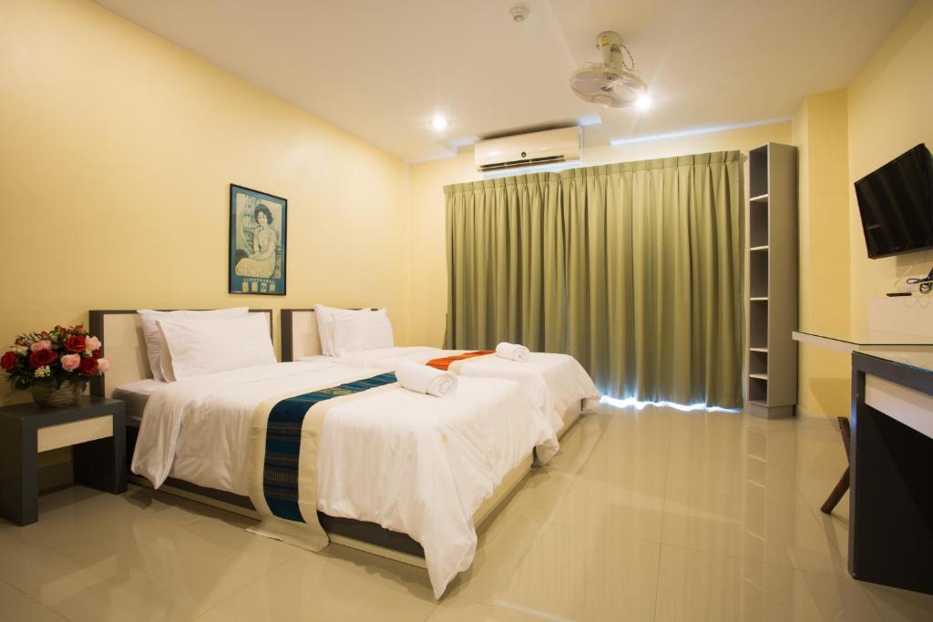 a hotel room with two beds and a television at Central Residences in Phuket