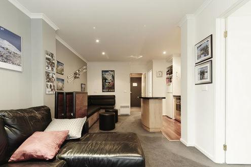 a living room with a leather couch and a kitchen at Valley View 203 in Mount Buller