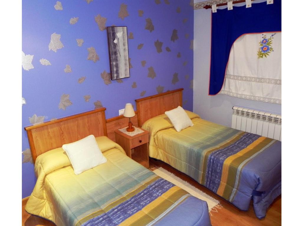 two beds in a room with blue walls at O Lar de Carmiña in Devesa