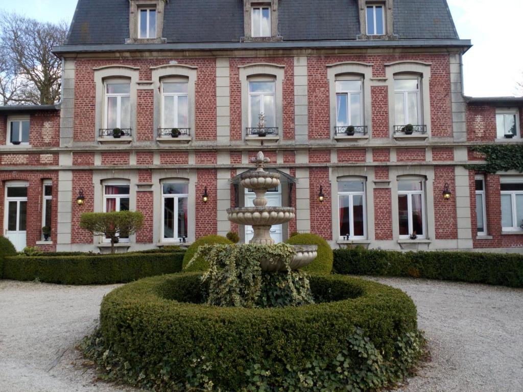 a fountain in front of a large building at Manoir le Louis XXI in Masnières