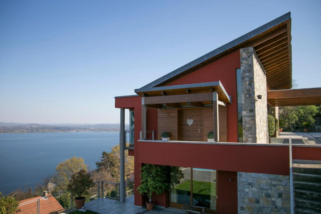 een rood huis met uitzicht op het water bij Paola's Apartment in Belgirate