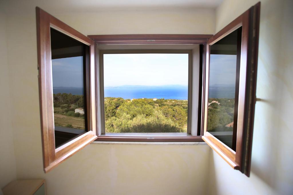 een open raam met uitzicht op de oceaan bij Hotel Paola in Carloforte