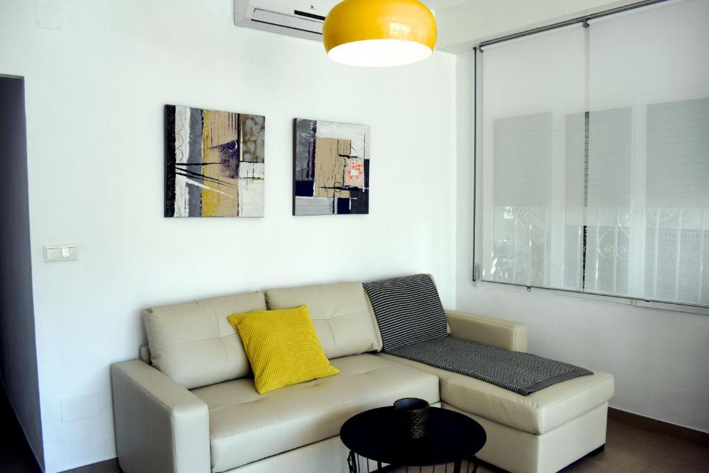 a living room with a couch and a yellow pillow at El Jardin BeNerja in Nerja