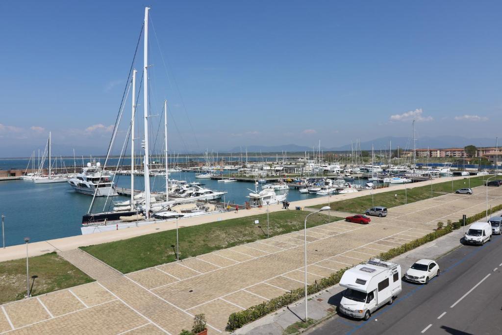 a marina with boats and cars parked next to a road at L'incanto Di Boccadarno in Marina di Pisa