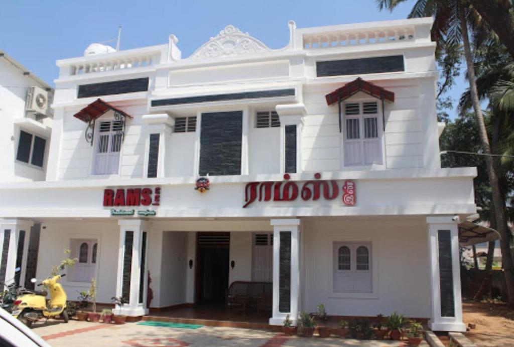Un bâtiment blanc avec un panneau. dans l'établissement Rams Inn, à Thanjavur