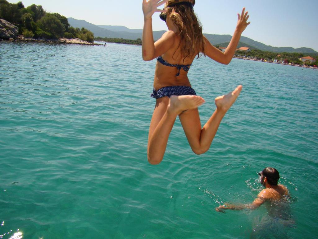 Kobieta skacząca do wody w jeziorze w obiekcie Apartment Bonaca Klek w mieście Klek