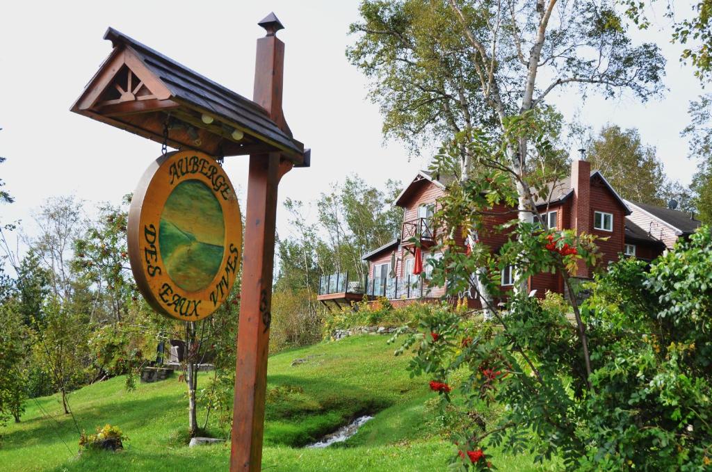 un panneau devant une maison avec une maison dans l'établissement Auberge des Eaux Vives, à La Malbaie