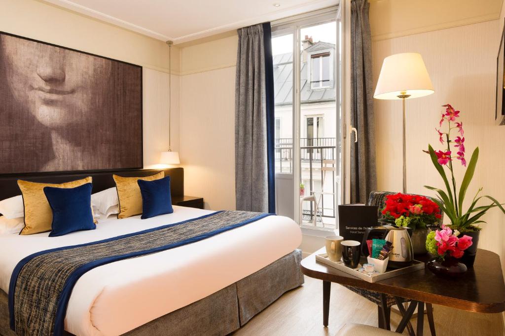 a hotel room with a bed and a large window at Hôtel Chaplain Paris Rive Gauche in Paris